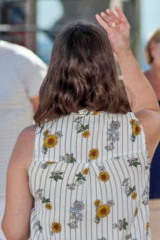 Catania. Italy - March 11, 2025: Woman delivering a dynamic speech to an engaged audience in a natural outdoor setting, wearing a sleeveless vibrant patterned top.