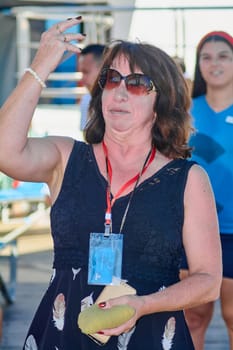 Catania. Italy - March 11, 2025: Woman aiming her toss during an engaging outdoor cornhole game, reflecting focus and casual enjoyment in a sunny and relaxed atmosphere.
