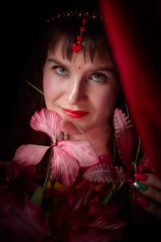 A mature blonde woman poses gracefully in an elegant sari, surrounded by blooming flowers, showcasing cultural beauty and vibrant colors.
