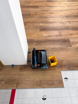 Broomfield, Colorado, USA-February 22, 2025-A close-up view of flooring installation tools placed on a partially completed wood laminate floor. The image shows a toolset, spacers, and an underlayment sheet, highlighting the ongoing home renovation process. The setup demonstrates the careful preparation and materials used for a smooth flooring installation.