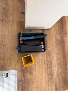 Broomfield, Colorado, USA-February 22, 2025-A close-up view of flooring installation tools placed on a partially completed wood laminate floor. The image shows a toolset, spacers, and an underlayment sheet, highlighting the ongoing home renovation process. The setup demonstrates the careful preparation and materials used for a smooth flooring installation.