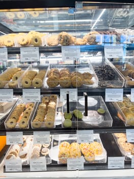 Castle Rock, Colorado, USA-February 22, 2025-A glass bakery display case filled with a variety of freshly baked cookies and sweet treats. Different types of cookies, including jam-filled, chocolate chip, and decorated sugar cookies, are neatly arranged in clear bins with labeled price tags. The well-lit display showcases an array of delicious baked goods available for purchase.