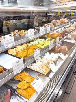 Castle Rock, Colorado, USA-February 22, 2025-A well-stocked Whole Foods deli case displaying a variety of fresh, prepared foods. The selection includes side dishes such as roasted vegetables, pasta salads, coleslaw, and other gourmet deli offerings. Each tray is labeled with pricing and descriptions, providing convenient meal options for customers.