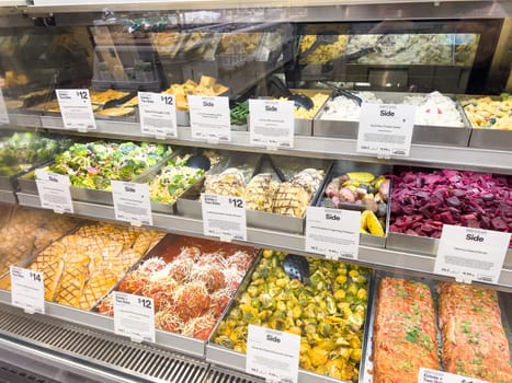 Castle Rock, Colorado, USA-February 22, 2025-A well-stocked Whole Foods deli case displaying a variety of fresh, prepared foods. The selection includes side dishes such as roasted vegetables, pasta salads, coleslaw, and other gourmet deli offerings. Each tray is labeled with pricing and descriptions, providing convenient meal options for customers.
