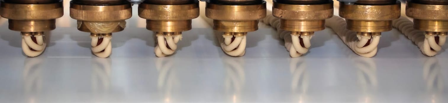 A series of precision nozzles are arranged neatly, connected by tubing, showcasing a component of industrial machinery in a manufacturing facility.
