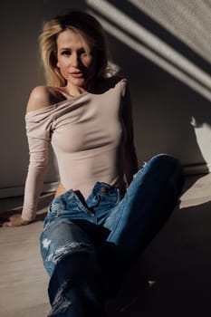 Beautiful slim fashion blonde woman in jeans by the window
