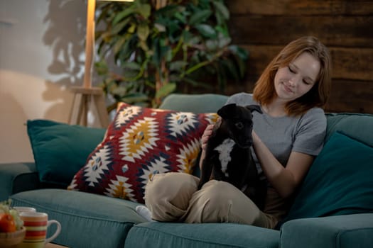 A young woman is enjoying quality time with her adorable dog while relaxing on a couch in a cozy living room,