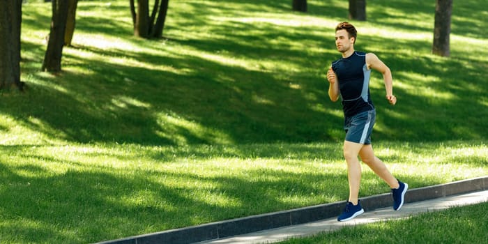 Healthy lifestyle workout and park. Young man in sportswear with fitness tracker runs along the track