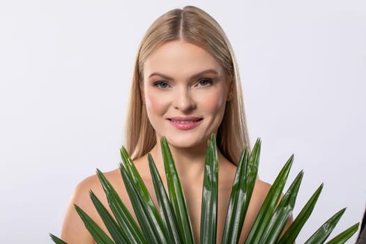 A cheerful woman strikes a pose surrounded by lush green leaves, beautifully showcasing her natural beauty and serenity