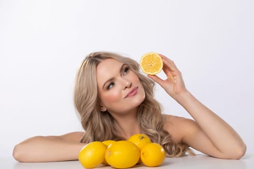 A stunningly beautiful model happily poses with fresh, juicy lemons, beautifully embodying freshness and vitality