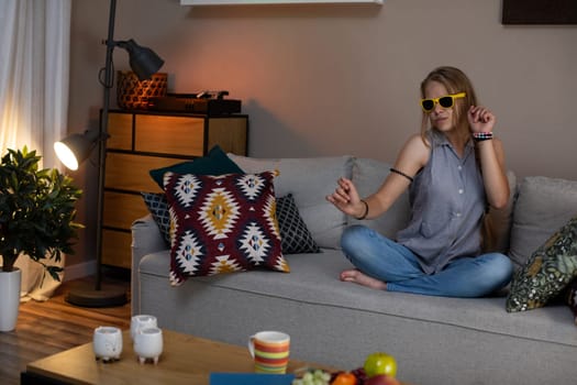 In a relaxed evening scene, a person wearing stylish sunglasses is enjoying their warm and cozy living space