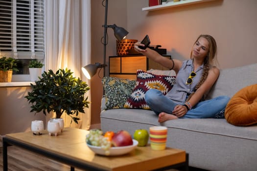 A woman enjoys a cozy evening in a warm living room filled with delicious snacks and vibrant plants