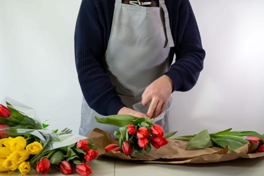 Adult caucasian male florist arranging tulip bouquets.