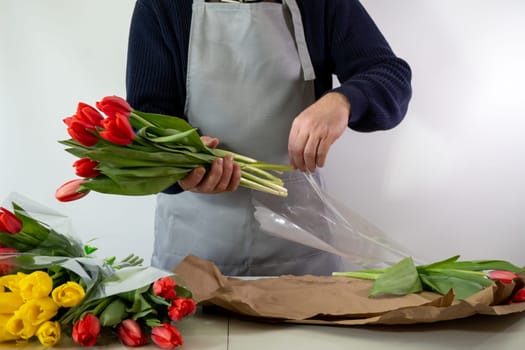Florist wrapping tulips with care in apron.