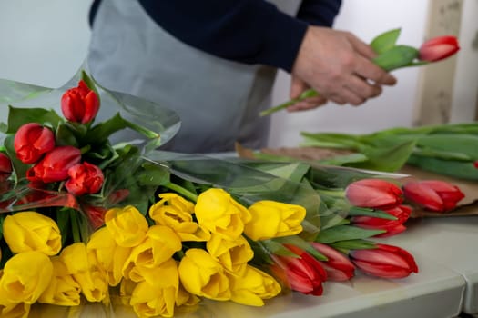 Florist adult men arranging colorful tulips in shop