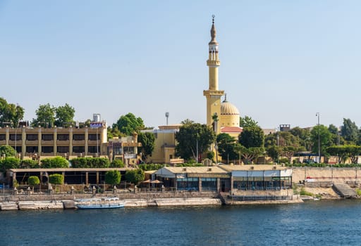 Luxor, Egypt - 2 November 2024: Luxor's waterfront along the Nile River, featuring a mosque, hotel, and restaurant on a clear day.