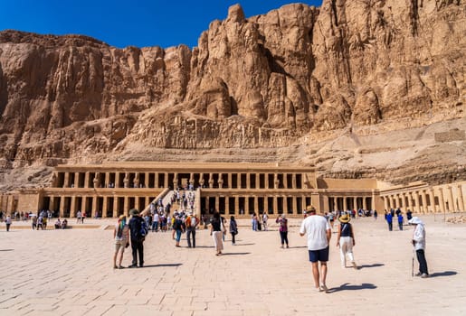 Luxor, Egypt - 2 November 2024: Tourists walk to the Mortuary Temple of Hatshepsut which stands majestically against the dramatic cliffs