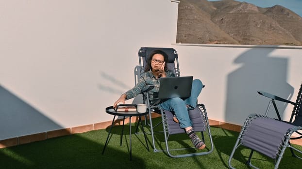 A freelancer enjoys remote work on a terrace, combining productivity with leisure, surrounded by nature.