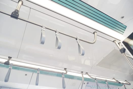 Ceiling view of a train showing modern hanging straps for passengers.