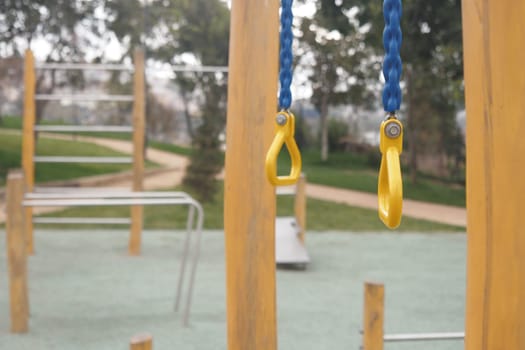 Quiet playground with yellow swings and climbing frames under trees.