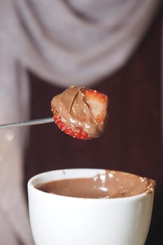 Dipping a fresh strawberry into rich chocolate at a gathering with friends.