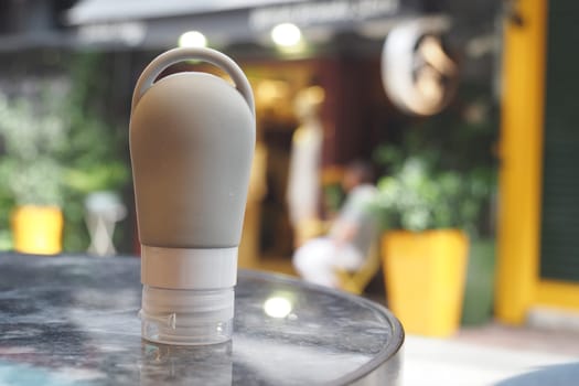 A reusable squeeze bottle sits on a table while people relax nearby.