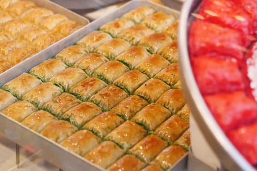 Assorted baklava pieces arranged neatly in trays at a pastry shop.