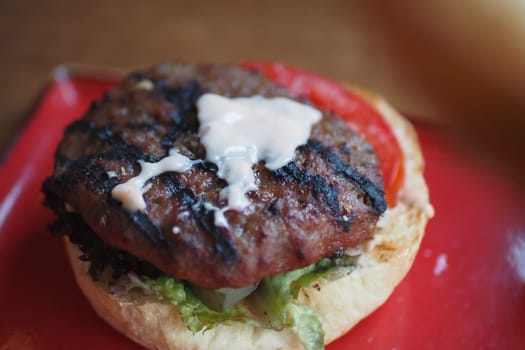 A delicious grilled hamburger topped with lettuce and tomato sits on a plate.