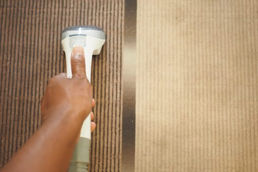 Person uses a handheld cleaner on carpet, focusing on dirt removal.