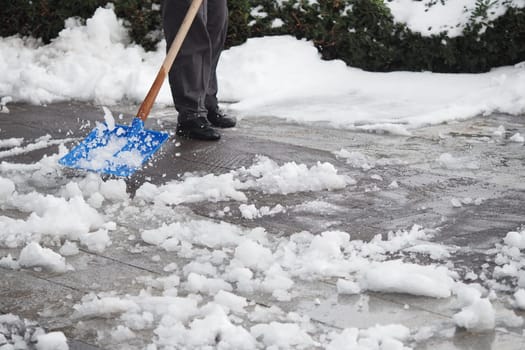 A person clears snow from a walkway using a shovel on a cold day.