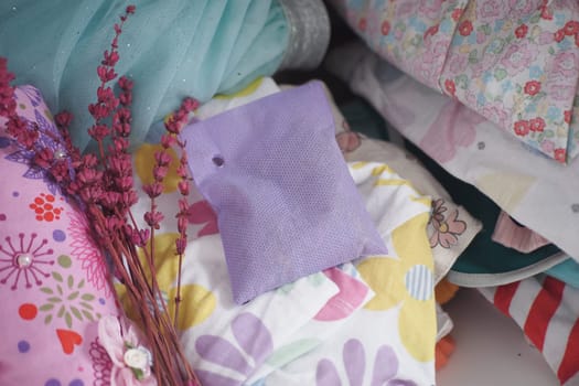 Textiles in various patterns and colors are layered with dried flowers nearby.