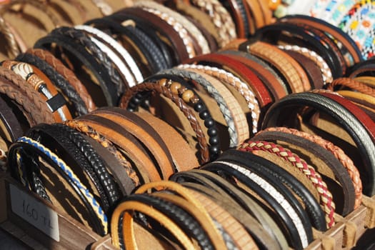 Assortment of colorful leather bracelets for sale at a sunny market.