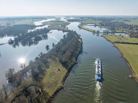 DEVENTER, NETHERLANDS - MARCH 8, 2025: Aerial view of a cargo ship sailing on the IJssel river, a branch of the Rhine river..