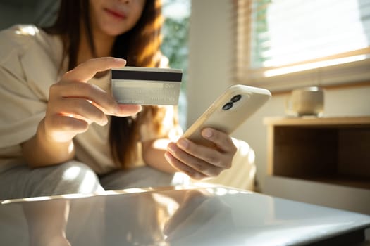 Woman holding credit card while using smartphone for online transactions or digital payments.