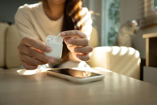 Woman taking out her wireless earbuds from charging case, ready to enjoy music or podcast.