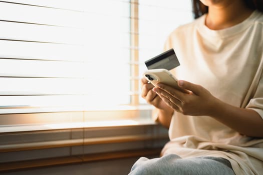Close up of woman making an online purchase using a credit card and mobile phone..