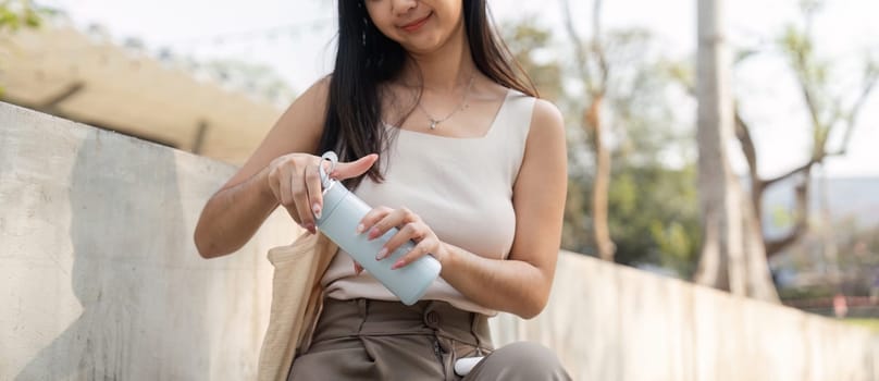 A young woman prepares her reusable cup in a serene outdoor setting, highlighting her commitment to a sustainable lifestyle.