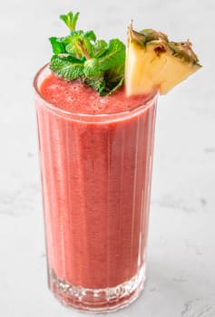 Creamy tropical smoothie with cherry, banana, and pineapple, garnished with mint and pineapple