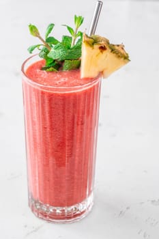 Creamy tropical smoothie with cherry, banana, and pineapple, garnished with mint and pineapple