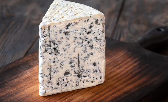 Creamy, veined Roquefort cheese with bold flavor, elegantly placed on a wooden board