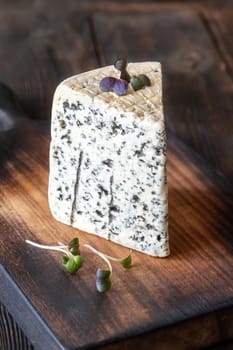 Creamy, veined Roquefort cheese with bold flavor, elegantly placed on a wooden board