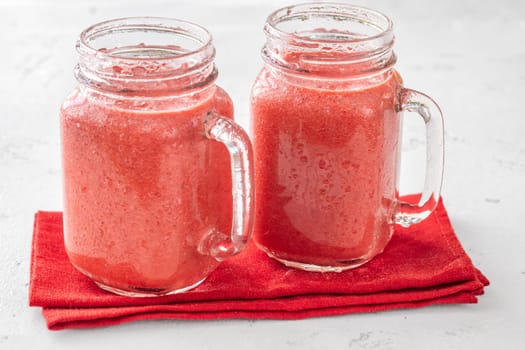 Creamy tropical smoothie with cherry, banana, and pineapple in mason jars