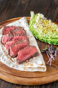 Juicy, perfectly sliced steak resting on a tortilla with fresh nappa cabbage