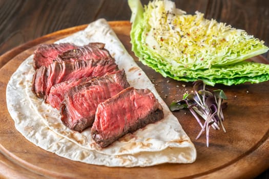 Juicy, perfectly sliced steak resting on a tortilla with fresh nappa cabbage