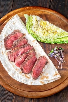 Juicy, perfectly sliced steak resting on a tortilla with fresh nappa cabbage