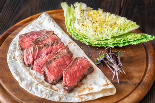 Juicy, perfectly sliced steak resting on a tortilla with fresh nappa cabbage