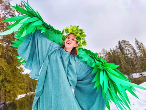 Cheerful girl dressed in a green outfit stands by a tranquil lake, embodying the spirit of spring and fantasy in a role-playing scene.