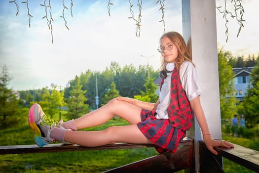 A girl dressed in a stylish outfit relaxes on a railing, showcasing a fun and carefree moment in a vibrant outdoor park.