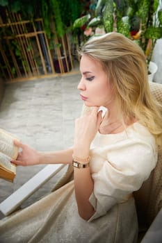 A woman with blonde hair is quietly reading a book, showcasing her lifestyle as a middle-aged blogger in her home.