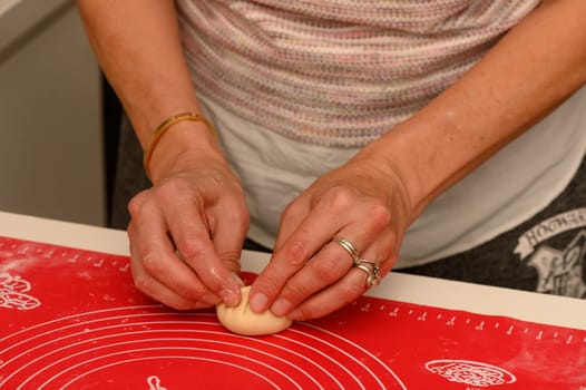 A devoted baker expertly molds a small ball of dough, showcasing craftsmanship in a cozy kitchen atmosphere.